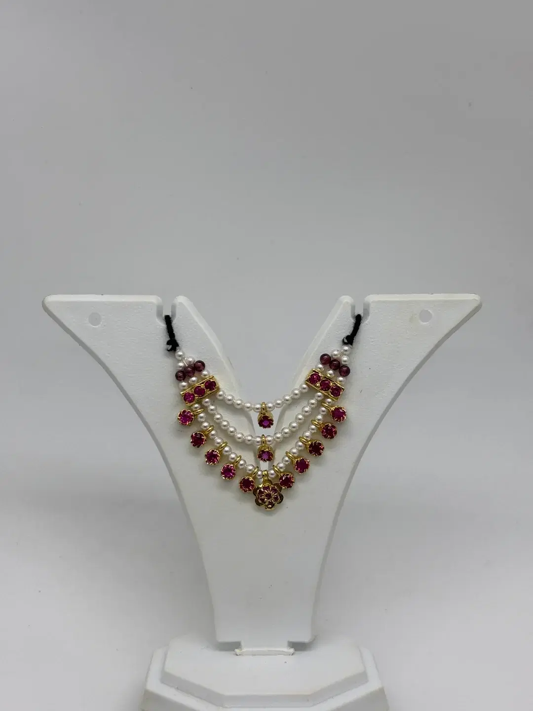 Three-strand pearl haar with silver ruby bar chowkis, dangling ruby bezels, and rosette pendant for Laddu Gopal